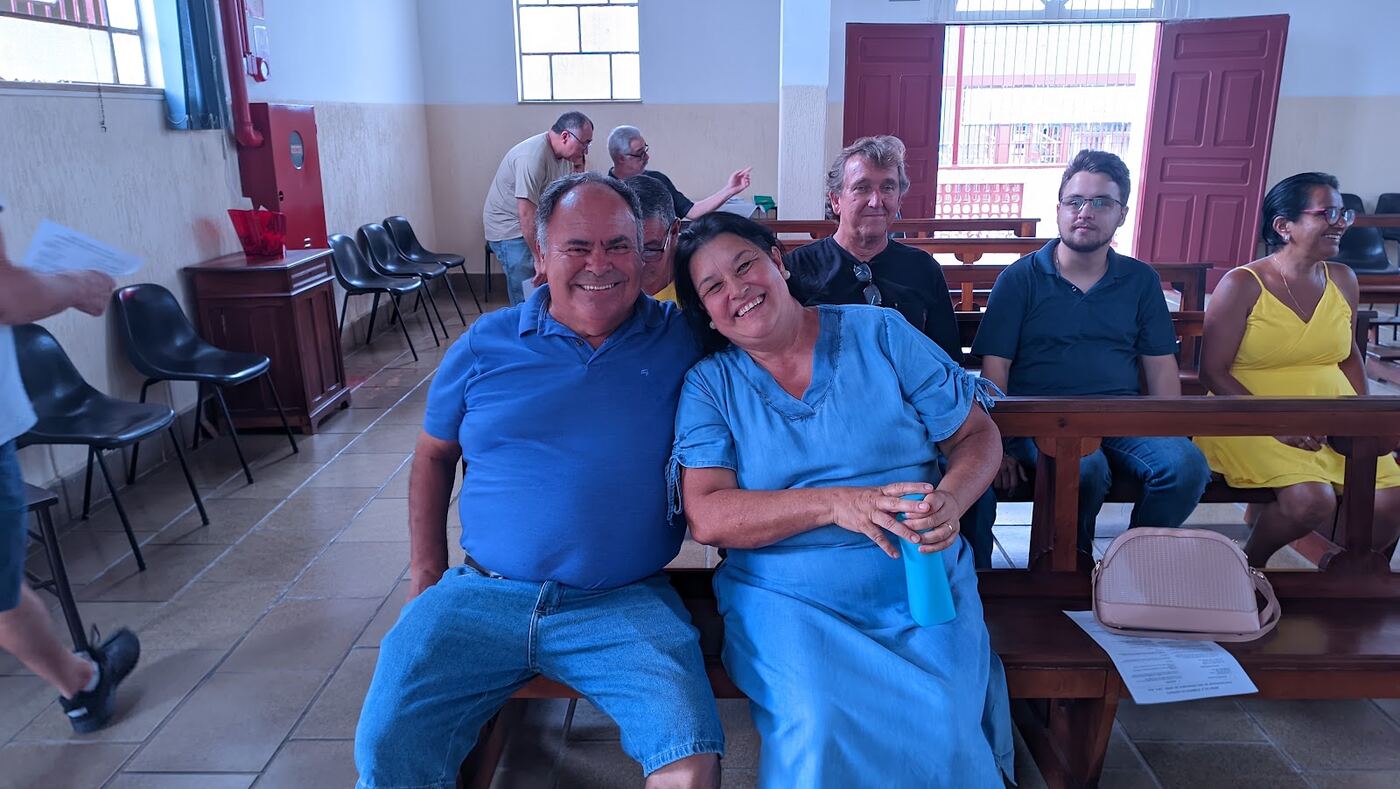 Casal de irmãos sorrindo sentados nos bancos após a celebração
