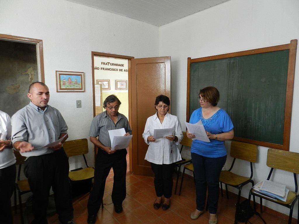 Irmãos e irmãs da fraternidade de pé, rezando juntos com as folhas de oração nas mãos